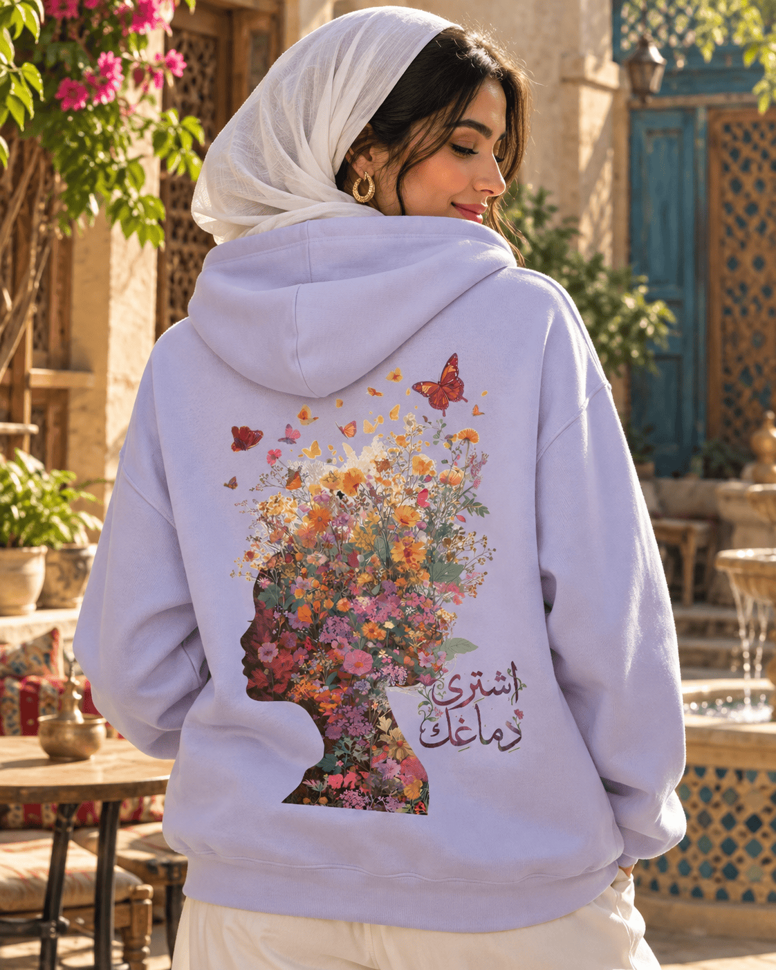 Woman wearing the Ishtiry Dimaghek اشتري دماغك floral head hoodie in Orchid in a sunny courtyard, by Cairo NYC