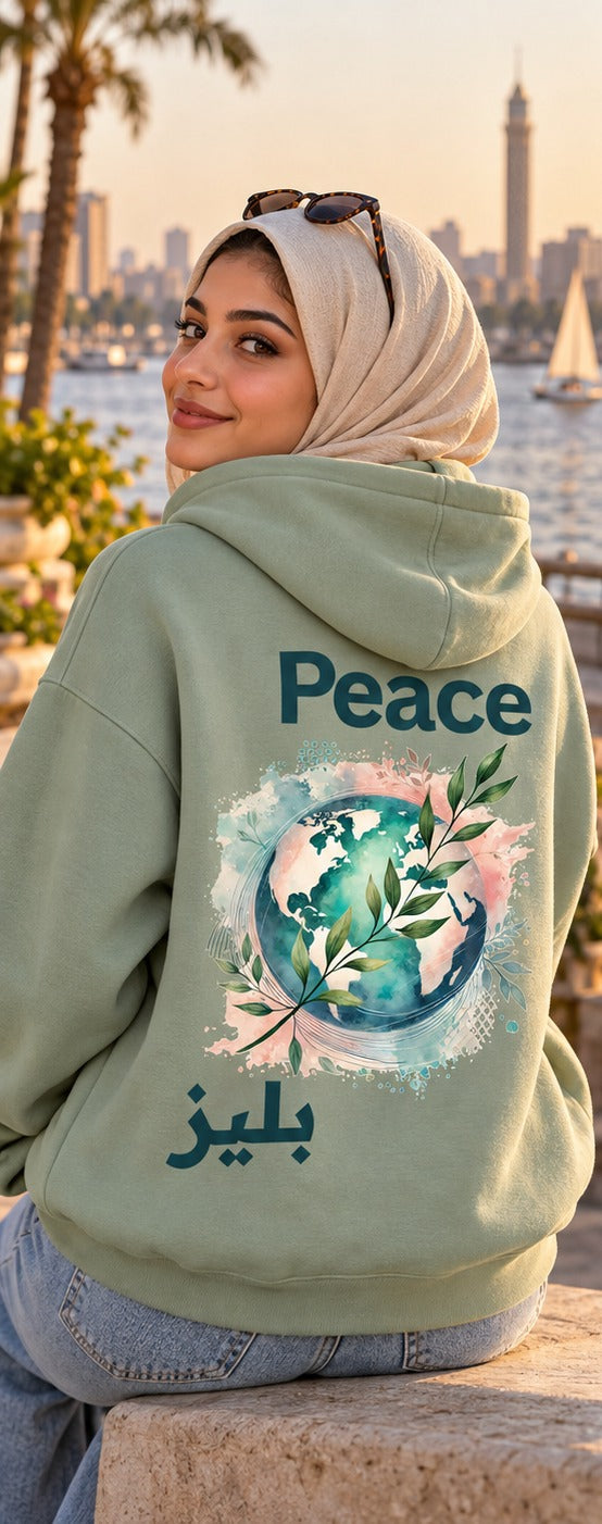 Back of a sage green Peace بليز Arabic hoodie with a watercolor globe and olive branch, worn by the Nile at sunset